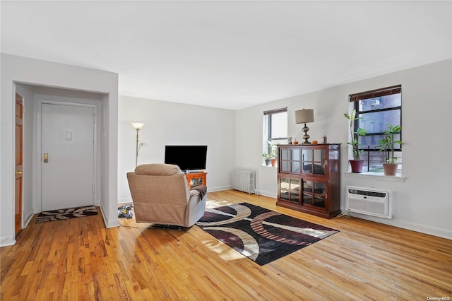 living room with radiator heating unit, light hardwood / wood-style floors, and a wall mounted air conditioner