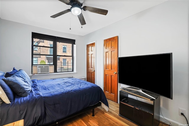 bedroom featuring ceiling fan, cooling unit, and hardwood / wood-style flooring