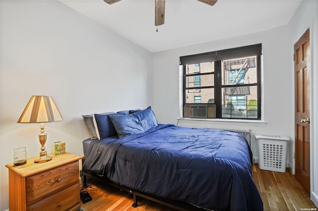 bedroom featuring ceiling fan, cooling unit, and hardwood / wood-style flooring