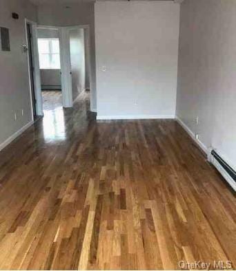 spare room featuring a baseboard radiator and dark wood-type flooring