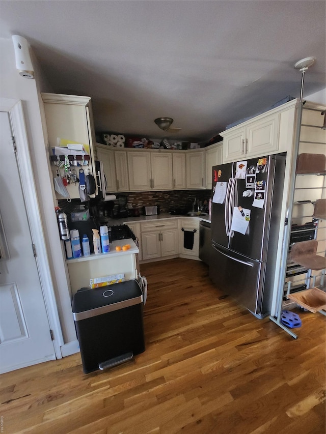 kitchen featuring white cabinets, dark hardwood / wood-style floors, decorative backsplash, and stainless steel refrigerator