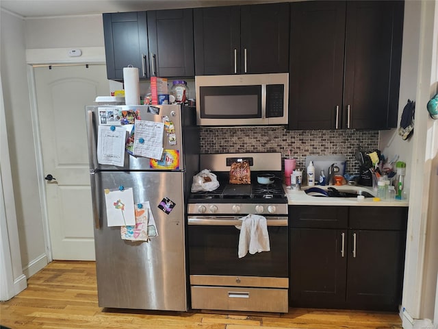 kitchen with backsplash, sink, light wood-type flooring, and appliances with stainless steel finishes