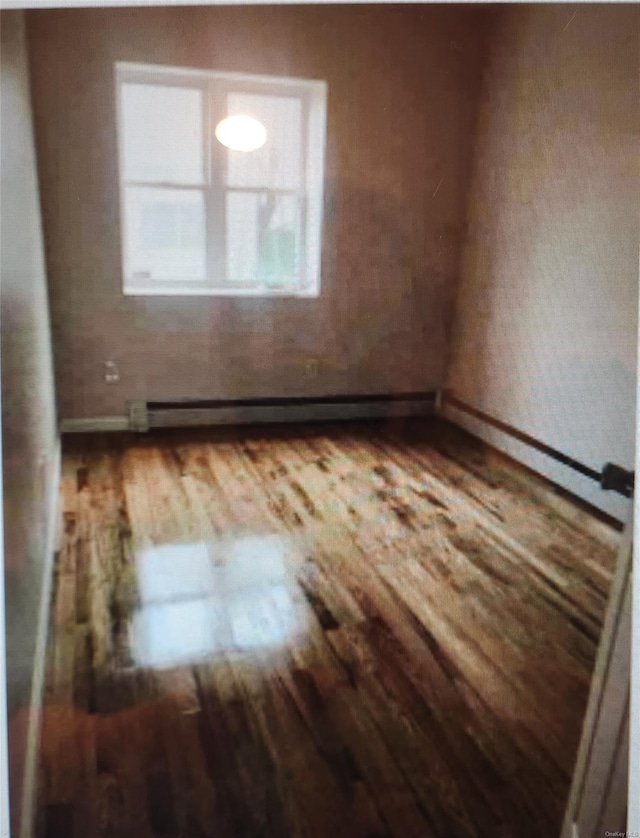 unfurnished room featuring hardwood / wood-style flooring and a baseboard radiator