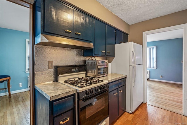 kitchen with a textured ceiling, white appliances, light hardwood / wood-style floors, and backsplash