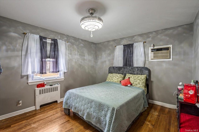 bedroom with an AC wall unit, radiator heating unit, and hardwood / wood-style flooring