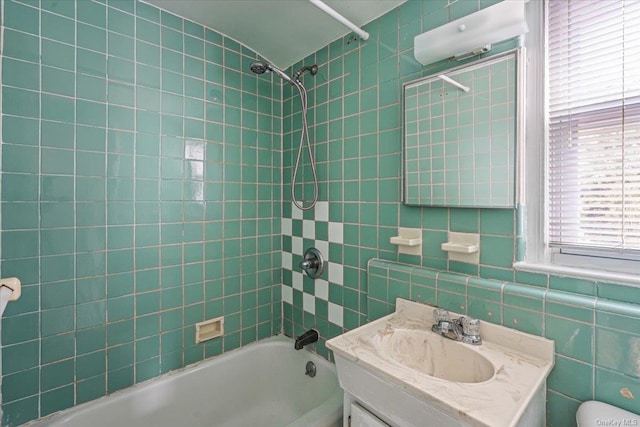 full bathroom with vanity, toilet, tile walls, and tiled shower / bath