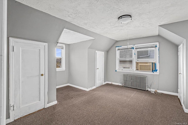 bonus room featuring dark carpet, radiator, a textured ceiling, vaulted ceiling, and cooling unit