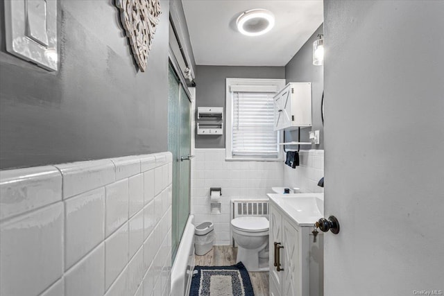 full bathroom with enclosed tub / shower combo, toilet, vanity, tile walls, and hardwood / wood-style flooring