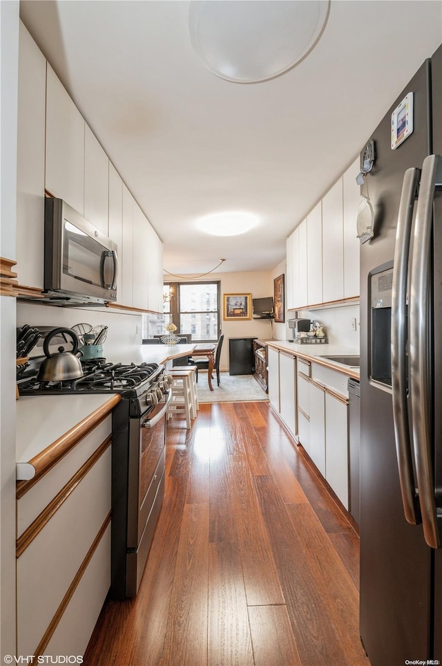 kitchen featuring appliances with stainless steel finishes, white cabinetry, and dark wood-type flooring