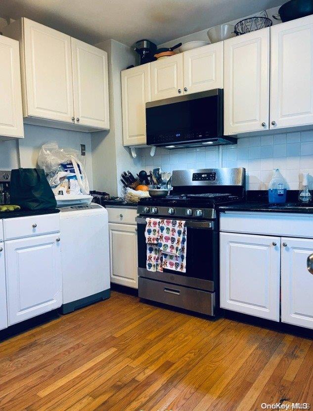 kitchen featuring backsplash, white cabinetry, wood-type flooring, and stainless steel appliances