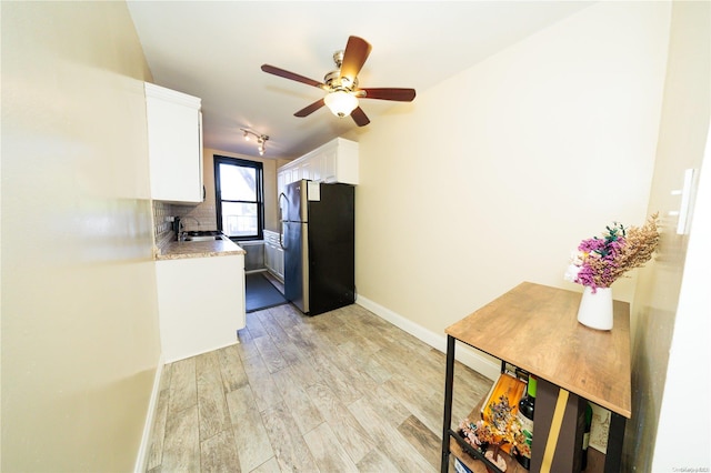 kitchen with white cabinets, sink, decorative backsplash, stainless steel fridge, and light hardwood / wood-style floors