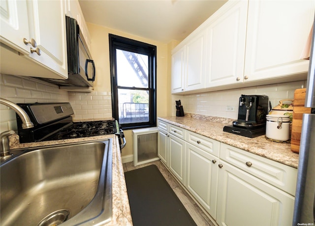 kitchen featuring decorative backsplash, white cabinetry, and sink