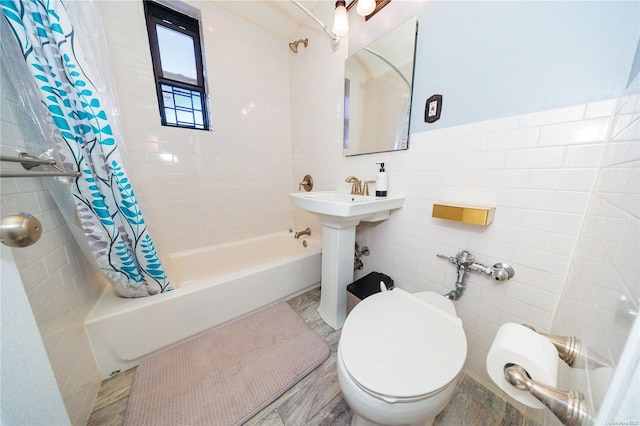 full bathroom with sink, toilet, tile walls, and shower / tub combo with curtain