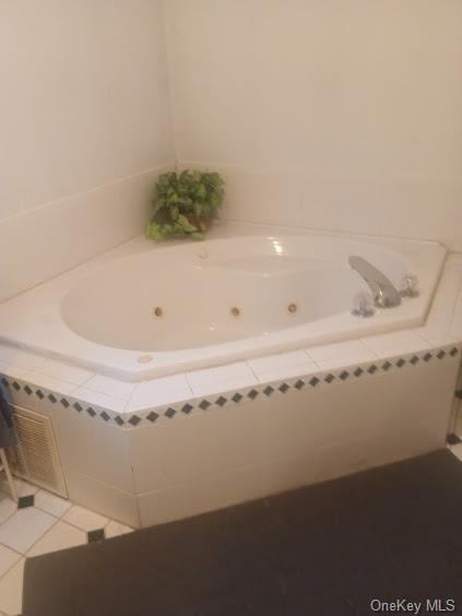 bathroom with tiled bath and tile patterned flooring