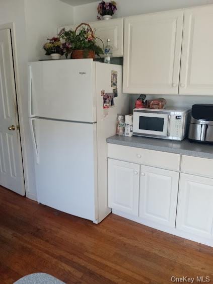 kitchen with dark hardwood / wood-style flooring, white cabinets, and white appliances