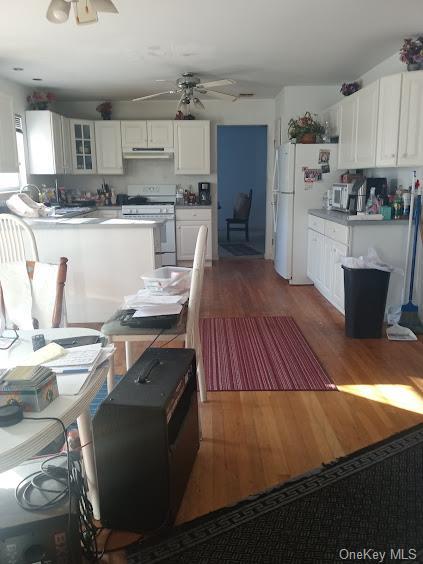 kitchen featuring hardwood / wood-style flooring, ceiling fan, white cabinetry, and white appliances