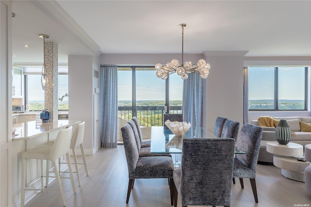 dining area with an inviting chandelier, ornamental molding, and light hardwood / wood-style flooring