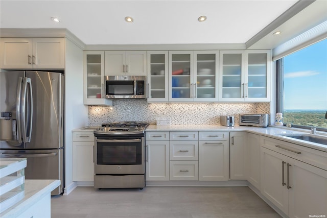 kitchen featuring backsplash, stainless steel appliances, sink, white cabinets, and light hardwood / wood-style floors