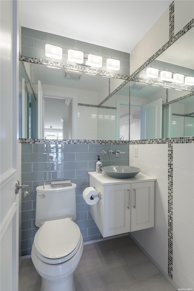 bathroom with tile patterned floors, vanity, tile walls, and toilet