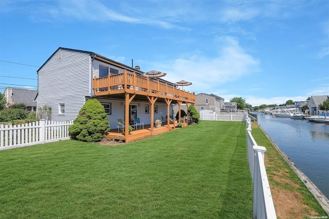 back of house featuring a deck with water view and a lawn