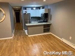 kitchen featuring white cabinetry, kitchen peninsula, appliances with stainless steel finishes, and light hardwood / wood-style flooring