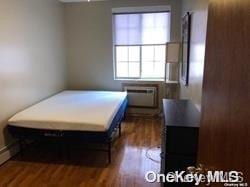 bedroom with dark hardwood / wood-style floors and a wall unit AC