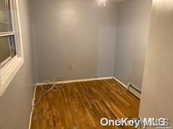 empty room featuring wood-type flooring and baseboard heating