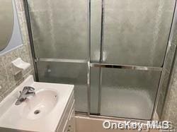 bathroom with vanity and combined bath / shower with glass door