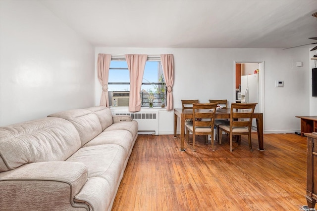 living room featuring cooling unit, wood-type flooring, and radiator heating unit