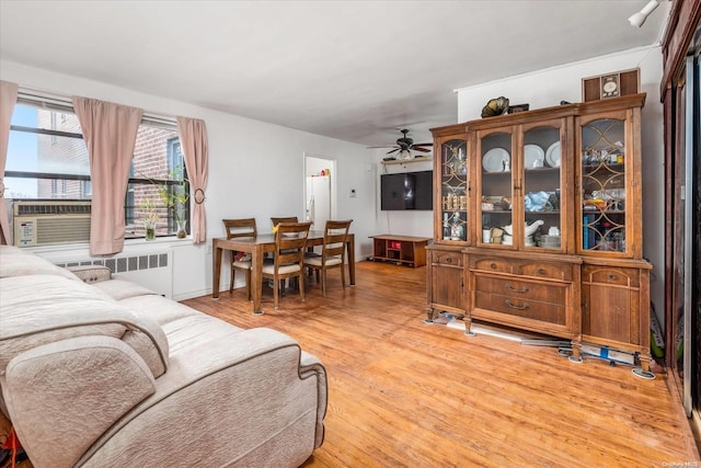 living room with radiator, ceiling fan, cooling unit, and light hardwood / wood-style floors