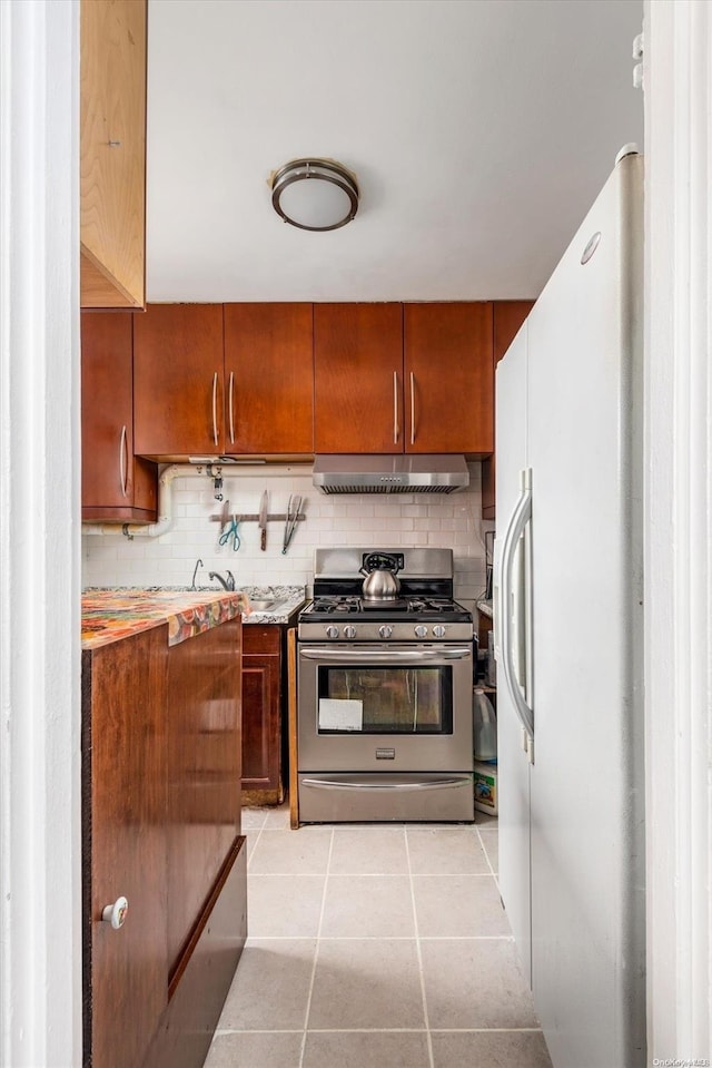 kitchen featuring light tile patterned flooring, decorative backsplash, white fridge with ice dispenser, and stainless steel range with gas stovetop