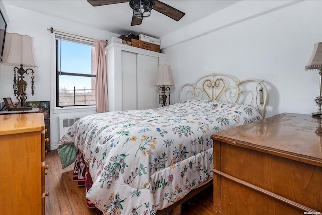 bedroom featuring a closet, radiator, ceiling fan, and dark hardwood / wood-style flooring