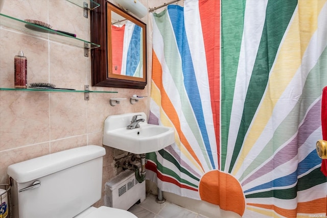 bathroom featuring toilet, tile walls, and sink