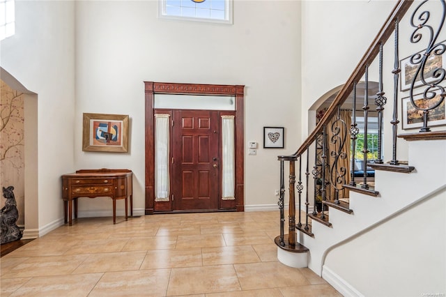 entrance foyer with light tile patterned floors and a towering ceiling