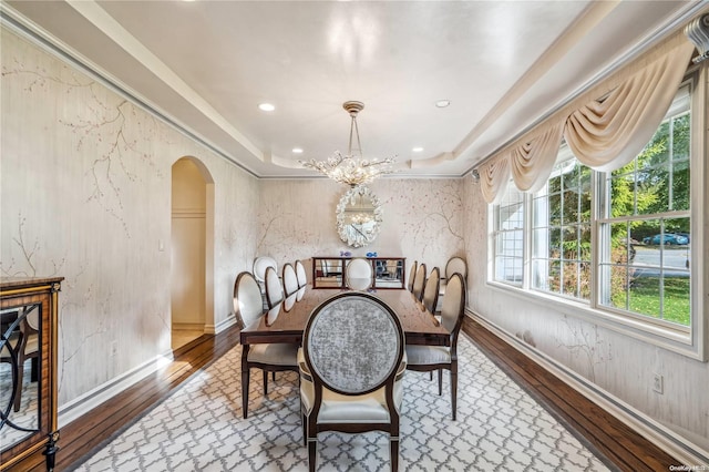 dining room featuring a raised ceiling, wood-type flooring, and an inviting chandelier