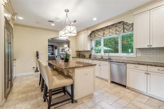 kitchen featuring dark stone counters, sink, pendant lighting, dishwasher, and a kitchen island