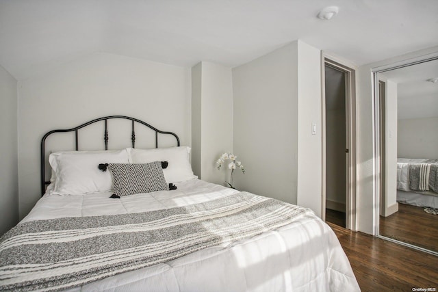 bedroom featuring dark hardwood / wood-style floors, vaulted ceiling, and a closet