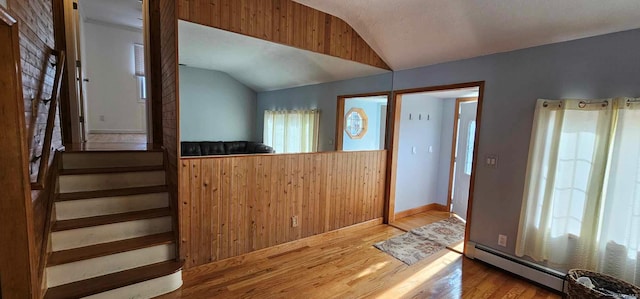 foyer entrance featuring hardwood / wood-style floors, vaulted ceiling, a healthy amount of sunlight, and a baseboard radiator