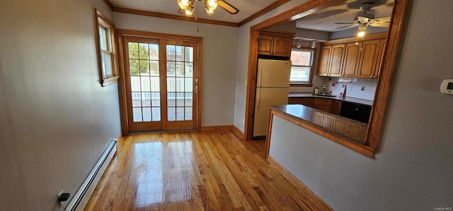 kitchen featuring baseboard heating, light hardwood / wood-style flooring, white fridge, and plenty of natural light