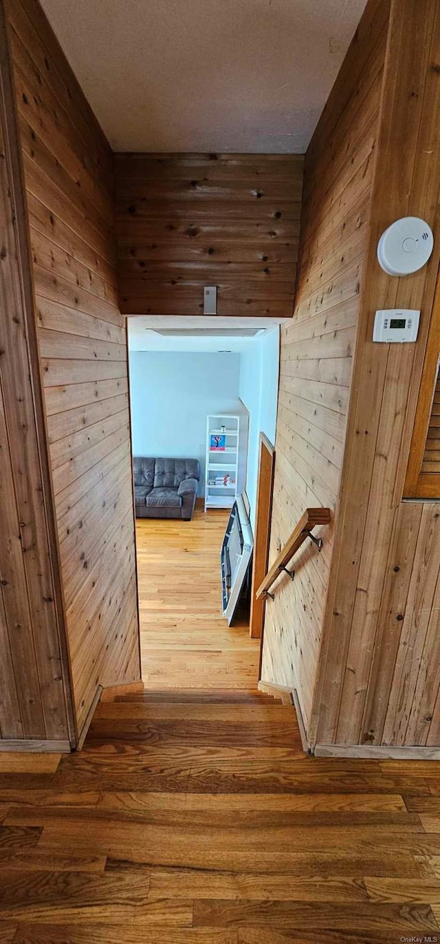 corridor with hardwood / wood-style floors and wood walls