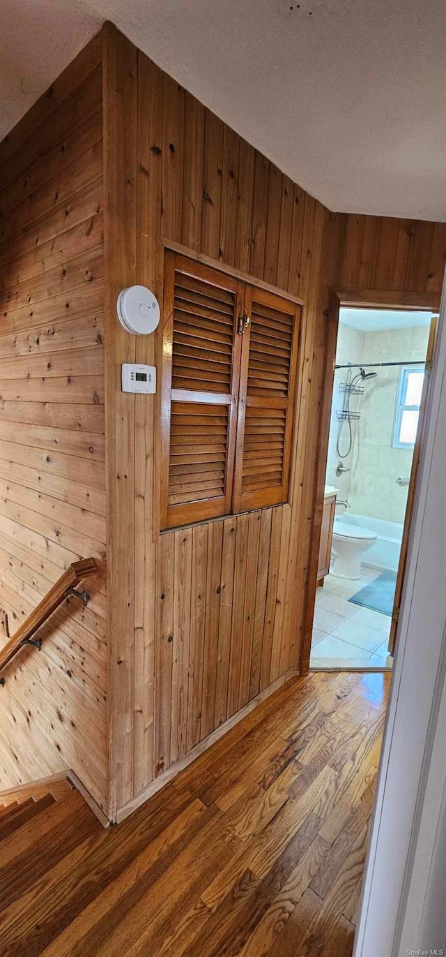 hallway featuring hardwood / wood-style floors, wood walls, and a textured ceiling