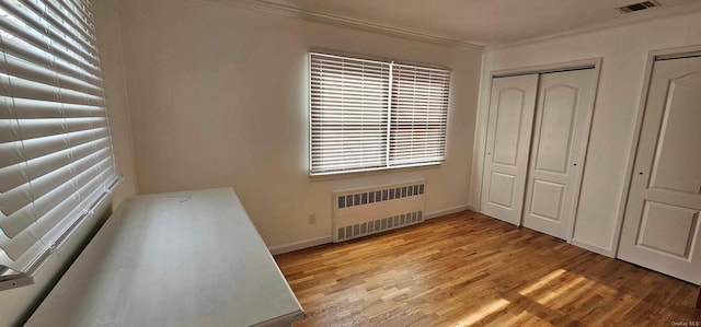 unfurnished bedroom with radiator heating unit, ornamental molding, and light wood-type flooring