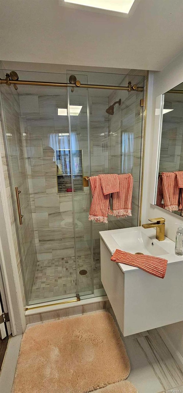 bathroom featuring a shower with door and vanity