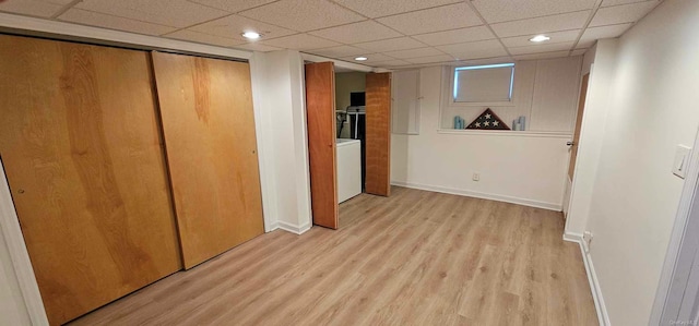 interior space featuring a paneled ceiling, washer / dryer, and light hardwood / wood-style flooring