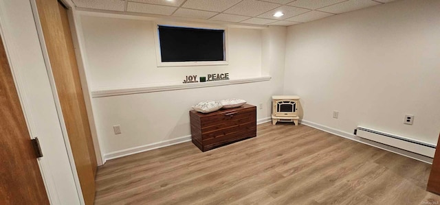 interior space featuring wood-type flooring, a baseboard radiator, and a drop ceiling