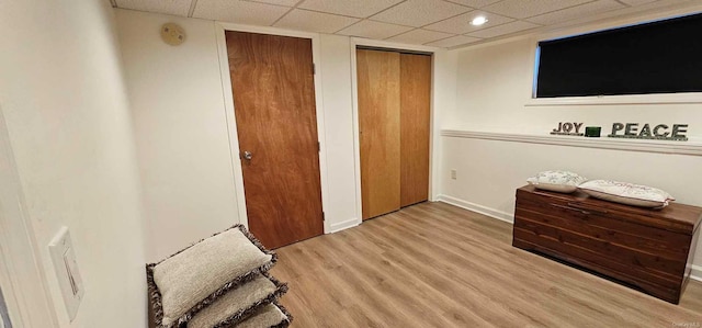 bedroom with multiple closets, a drop ceiling, and wood-type flooring