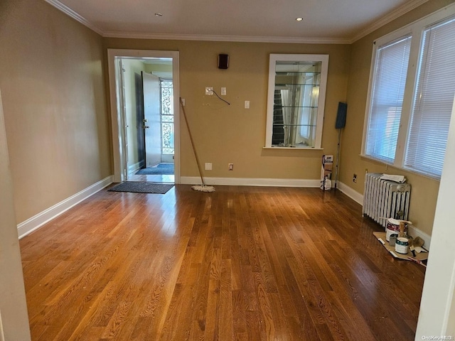 unfurnished room with hardwood / wood-style floors, radiator heating unit, and crown molding