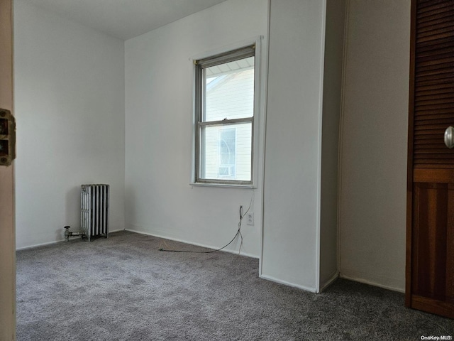 spare room featuring radiator and dark colored carpet