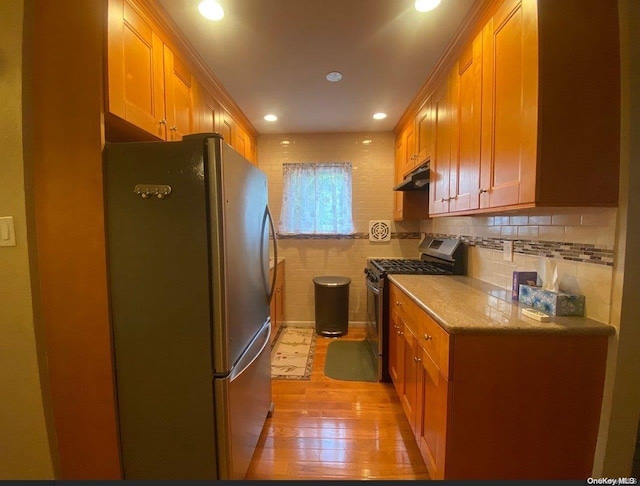 kitchen with tasteful backsplash, light wood-type flooring, and appliances with stainless steel finishes