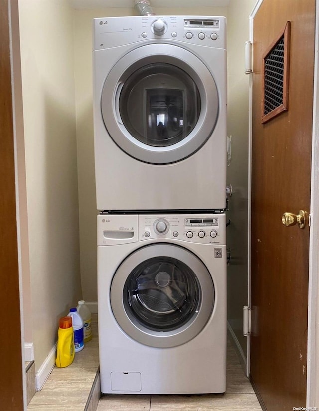 clothes washing area with light hardwood / wood-style flooring and stacked washer / dryer